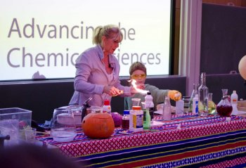 Science Magican Sue McGrath being helped by a young volunteer